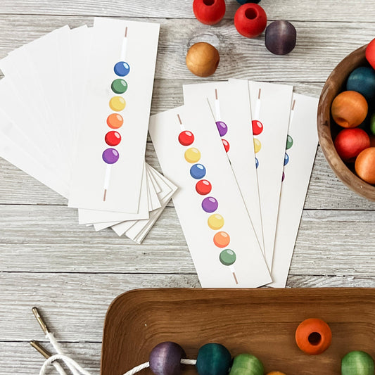 Colorful wooden beads on a wooden tray with cards and more beads on a wooden surface.