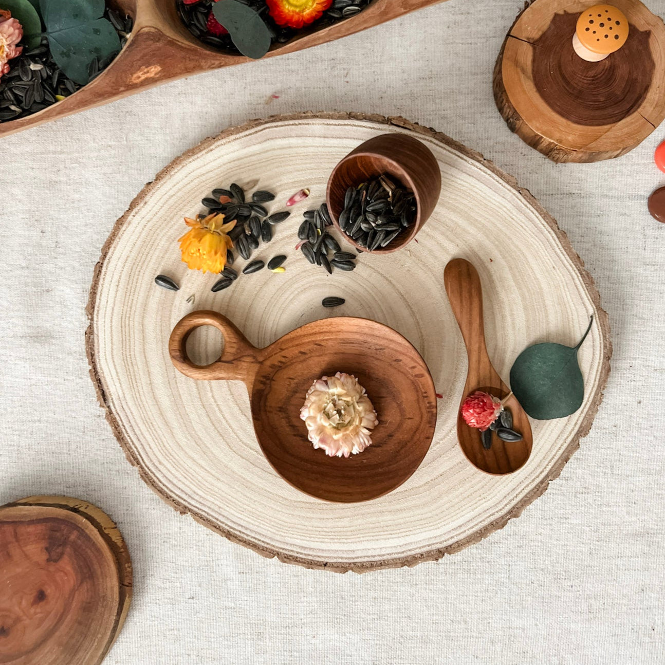 Wooden bowls and platters with dried flowers and leaves on a textured surface