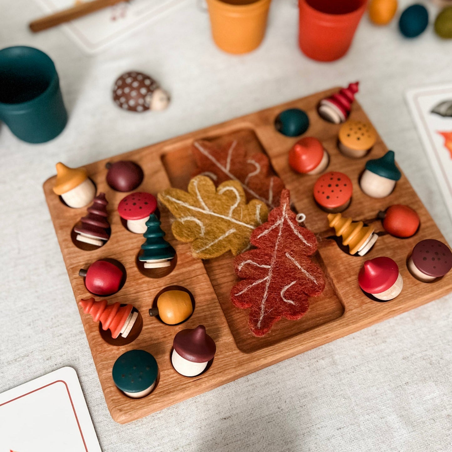 Wooden board with autumn-themed decorations on a light surface