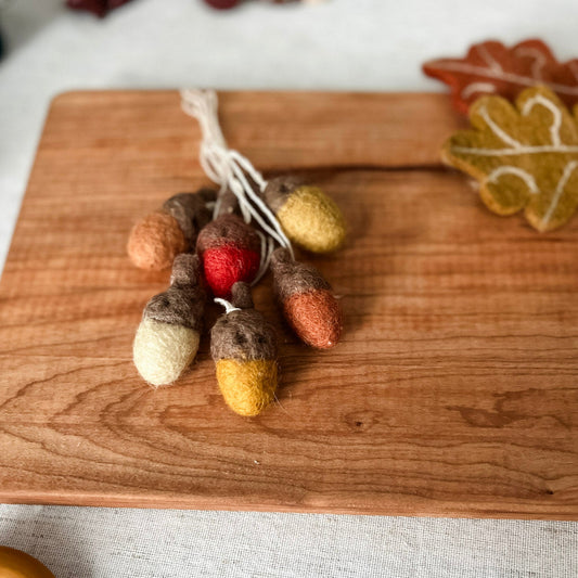 Decorative acorn ornaments on a wooden cutting board with a blurred background