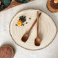Wooden spoons on a ceramic plate with decorative elements on a light surface