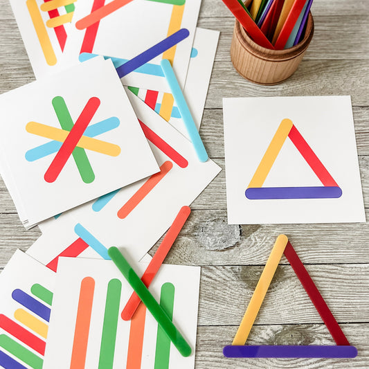 Colorful geometric shapes on white cards with wooden sticks on a wooden surface