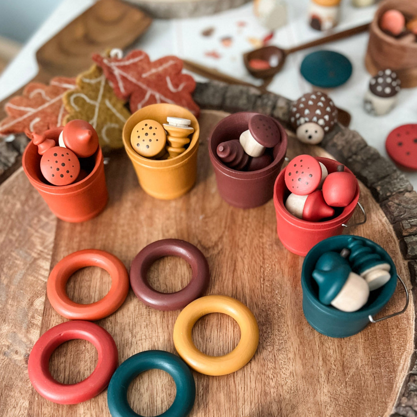 Colorful wooden rings and small pots on a wooden surface with a soft focus background.