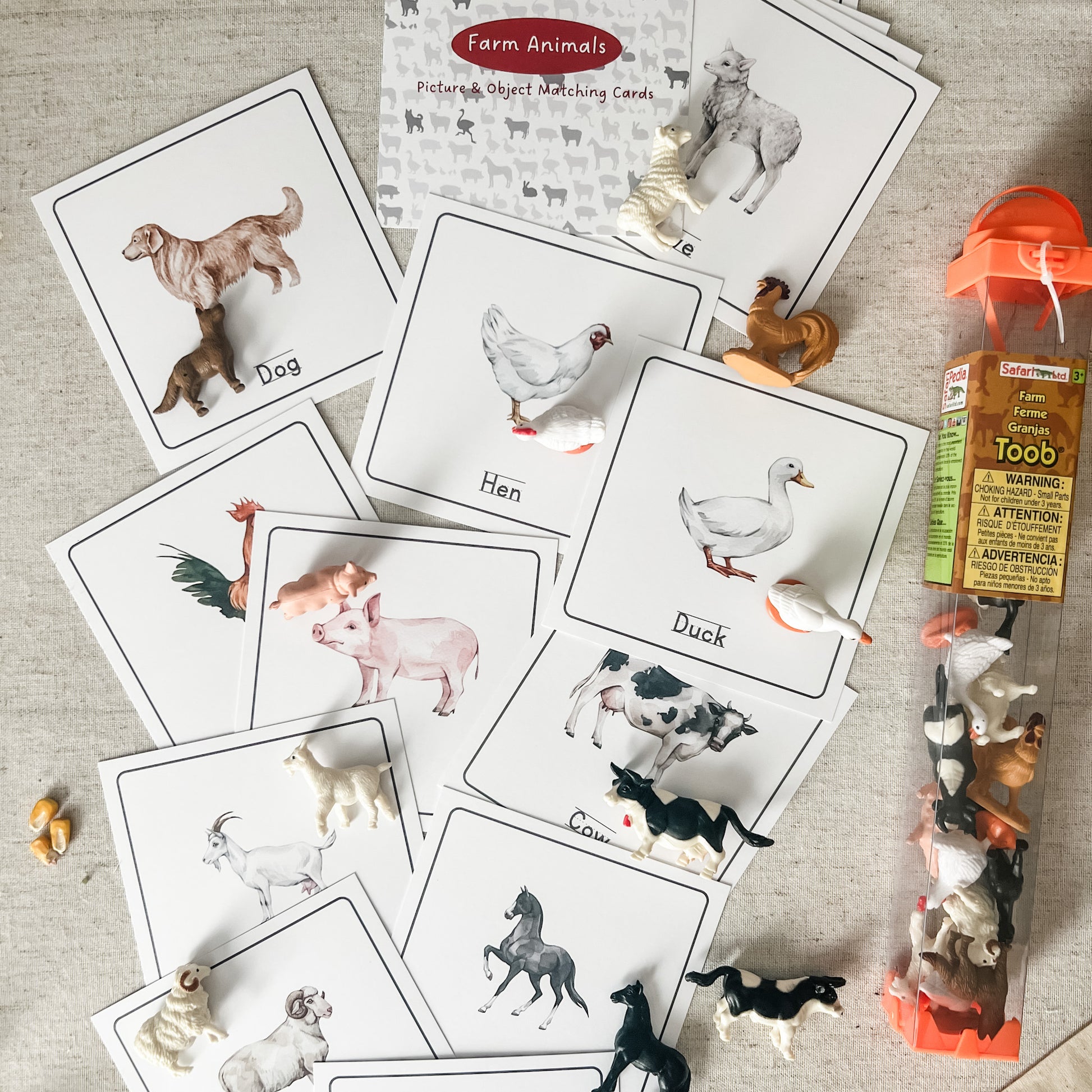 Educational farm animals card set with corresponding figurines on a textured surface.