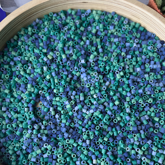 Close-up of blue and green beads in a wooden container